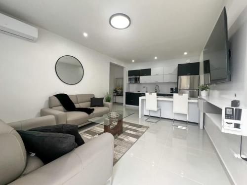 a white living room with a couch and a kitchen at Isabela Luxury Escape in Isabela