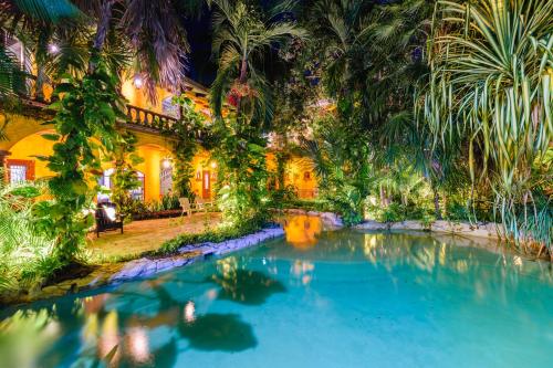 a swimming pool in front of a house with palm trees at La Hacienda Hotel, at Xcaret in Playa del Carmen