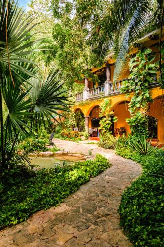 a building with a walkway in front of a yard at La Hacienda Hotel, at Xcaret in Playa del Carmen