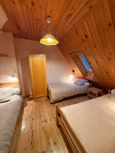 a bedroom with two beds in a wooden cabin at Le Domaine Belinay in Paulhac