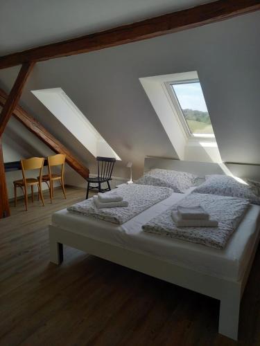 a bedroom with a bed and chairs in a attic at Farma Tasov in Velké Meziříčí