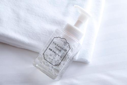 a bottle of hand sanitizer sitting on a bed at Hotel Hokke Club Shonan Fujisawa in Fujisawa