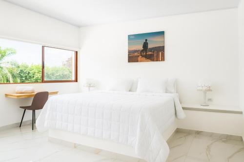 a white bedroom with a white bed and a desk at Riviera Hotel Boutique in Cali