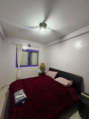 a bedroom with a bed with a red comforter at Palm Beach in Mansouria