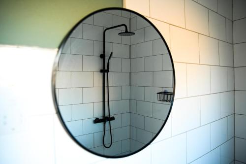 a round mirror in a bathroom with a shower at Luxe Residence Guest House in Kasane