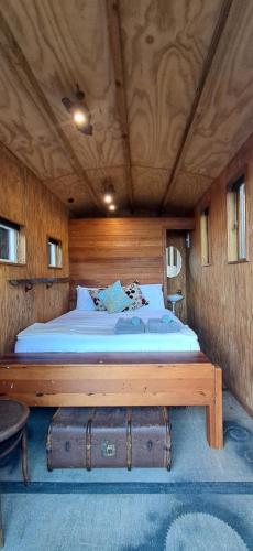 a bed in a room with a wooden ceiling at The Clearing - Rustic Wagon by the Sea in Picton