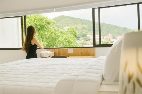 a woman standing in a bedroom looking out the window at Riviera Hotel Boutique in Cali