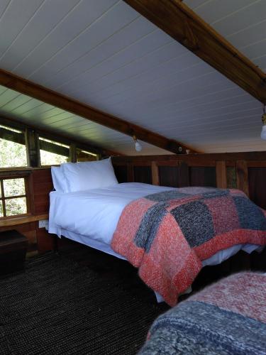 a bed in the middle of a room in a boat at Boutique Vintage Forest Cabin in Stormsrivier