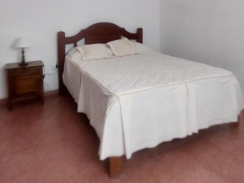 a bedroom with a white bed with a wooden headboard at La casa de Los Patitos in Arroyo de Los Patos