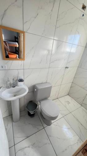 a white bathroom with a toilet and a sink at Sobrado Maré Mansa in Peruíbe