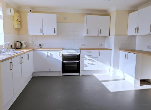 a kitchen with white cabinets and a black oven at Atherley House - Winter Sale! Spacious Self Catered Rooms in Southampton