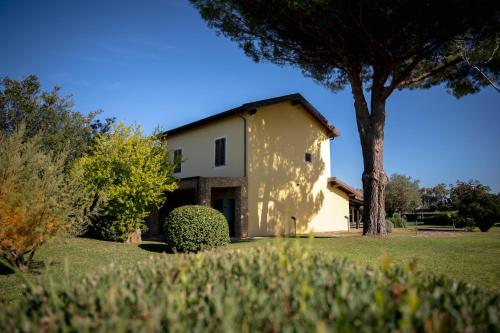 a white house with a tree in front of it at SU PASSU Country House in Fertilia