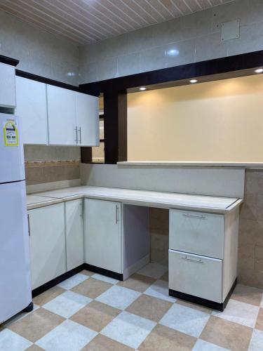 an empty kitchen with white cabinets and a refrigerator at شقق النزهة الفندقيه in Riyadh Al Khabra