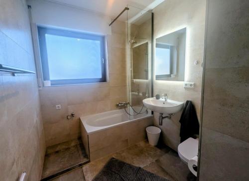 a bathroom with a sink and a tub and a toilet at Wohnen am Wald mit Pool & Sauna in Unterkirnach