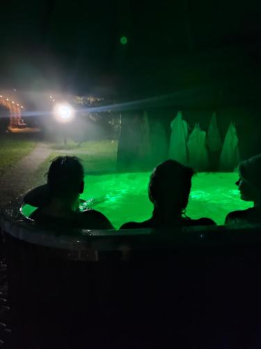 a group of people sitting in a hot tub at night at Całoroczne Domki "Stokrotka" in Solina