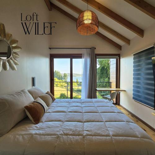 a large bed in a room with a large window at Loft Wilef in Tentén