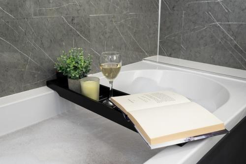 a book and a glass of wine sitting on a bath tub at Swanmere lodge, Lakeside view Pinelake Carnforth in Carnforth