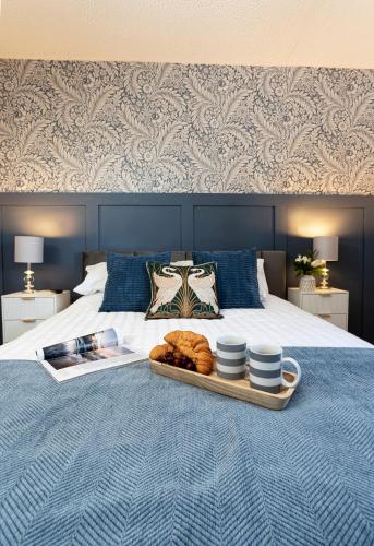 a tray of food on a bed with a tray of croissants at Swanmere lodge, Lakeside view Pinelake Carnforth in Carnforth