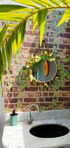 a bathroom sink with a mirror on a brick wall at Garden JP in João Pessoa