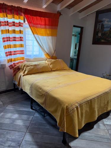 a bed in a room with a colorful curtain at House 3 blocks from downtown in Tepoztlán
