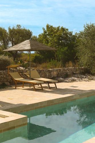 a picnic table and umbrella next to a swimming pool at Regina di Ulivi in Ostuni