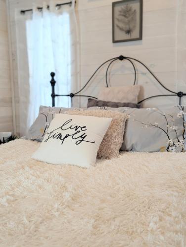 a white pillow with live strings written on it on a bed at Field and Fern Cottages in Tatamagouche