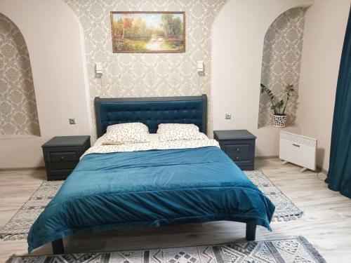 a bedroom with a blue bed and two night stands at Котедж Тиша in Rivnya