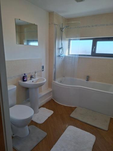 a bathroom with a tub and a toilet and a sink at Elegant three bedroom flat in Darlington