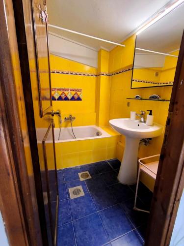 a yellow bathroom with a tub and a sink at Psalidi beach loft house in Psalidi