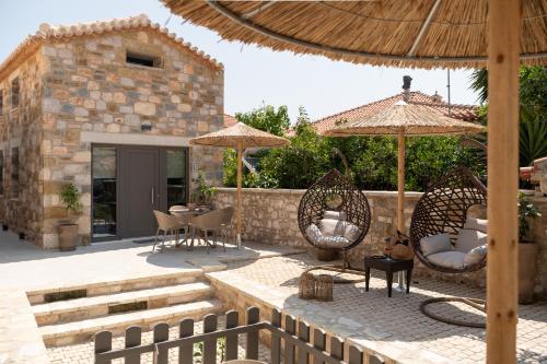 a patio with chairs and umbrellas next to a building at petra apartments apartment No3 in Methoni