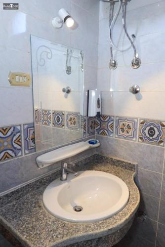 a bathroom with a sink and a mirror at Nefertari Palace apartments in Al Aqālitah