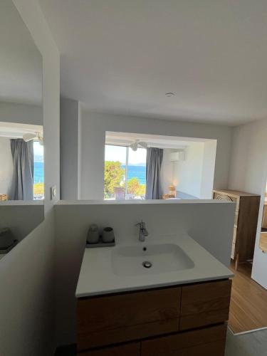 a white bathroom with a sink and a window at Villa Solanella in Coti-Chiavari