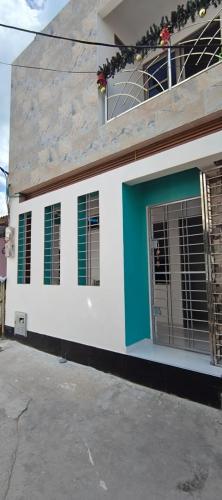 a building with green windows and a blue door at Hospedaje Saray Sofia in Coveñas