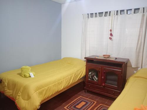 a bedroom with two beds and a table with a dog in it at Casa Ayres de la Quebrada in Humahuaca