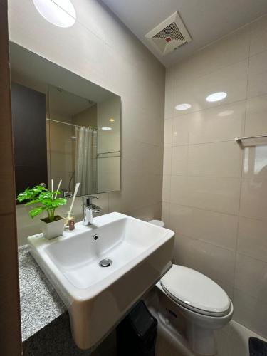 a bathroom with a sink and a toilet and a mirror at 35th Prime Staycation BGC in Manila