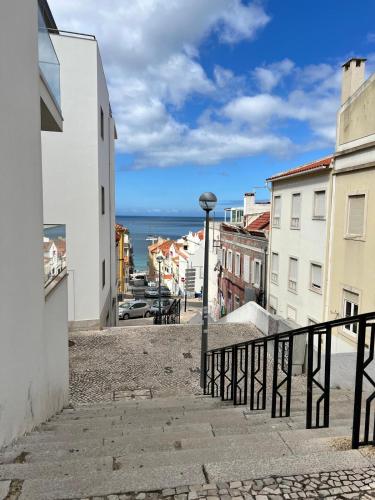 a city street with buildings and the ocean in the background at Duplex com Vista Mar a Passos da Praia - Just Sezimbra in Sesimbra
