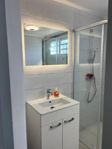 a white bathroom with a sink and a shower at Appartement Acajou Pool & Serenity in Le Lamentin