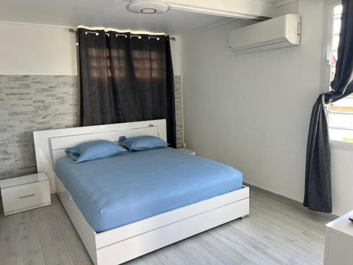 a bedroom with a bed with blue sheets and a window at Appartement Acajou Pool & Serenity in Le Lamentin