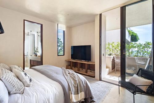 a bedroom with a large bed and a television at Beachfront 2BR Condo in Bahía Tankah, Tulum in Tancah