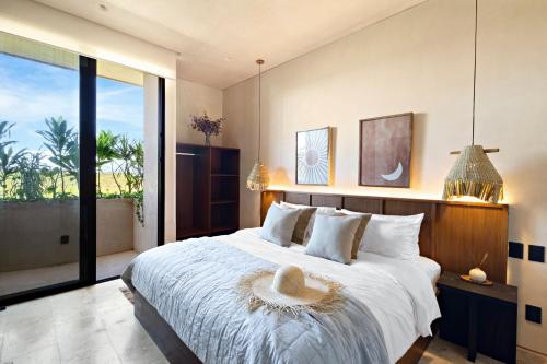 a bedroom with a large bed and a large window at Beachfront 2BR Condo in Bahía Tankah, Tulum in Tancah