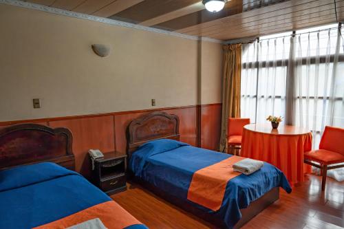 a bedroom with two beds and a table and chairs at Hostal Tukos La Casa Real in Potosí