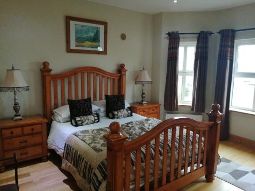 a bedroom with a bed and two nightstands and two windows at Rosswood House in Donegal
