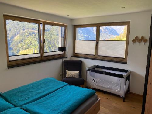 a bedroom with a bed and a chair and windows at Ferienwohnung Fotscherblick in Sellrain