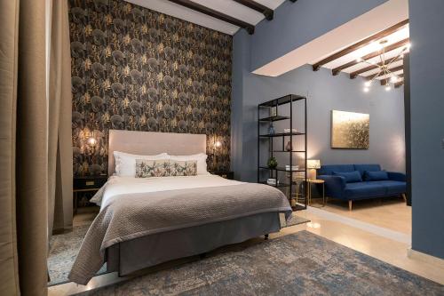 a bedroom with a bed and a blue chair at Boutique Suites in Arcos de la Frontera