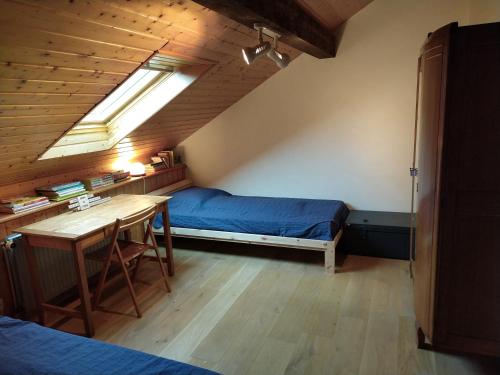 a bedroom with a bed and a desk and a window at Chalet les Pounets in Damprichard