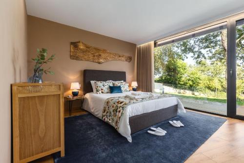 a bedroom with a bed and a large window at Casas De Bouro 3 Casa Do Alecrim in Terras de Bouro