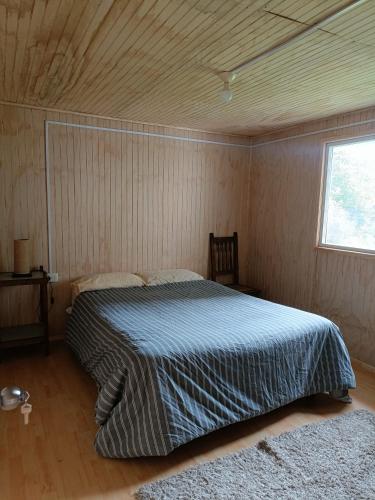 a bedroom with a bed in a room with a window at Cabaña Mañihueico in Hualaihué