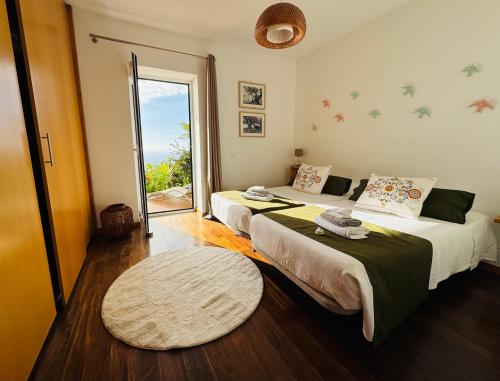 a bedroom with two beds and a large window at Villa Escola da Bica in Arco da Calheta