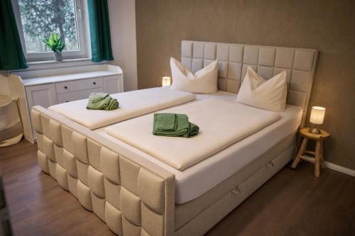 a large white bed with two green towels on it at *Premium-Apartment im Spreewald* in Burg