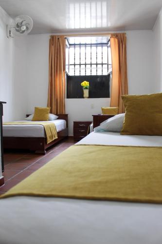 a hotel room with two beds and a window at Hotel Colonial San Felipe in Girón
